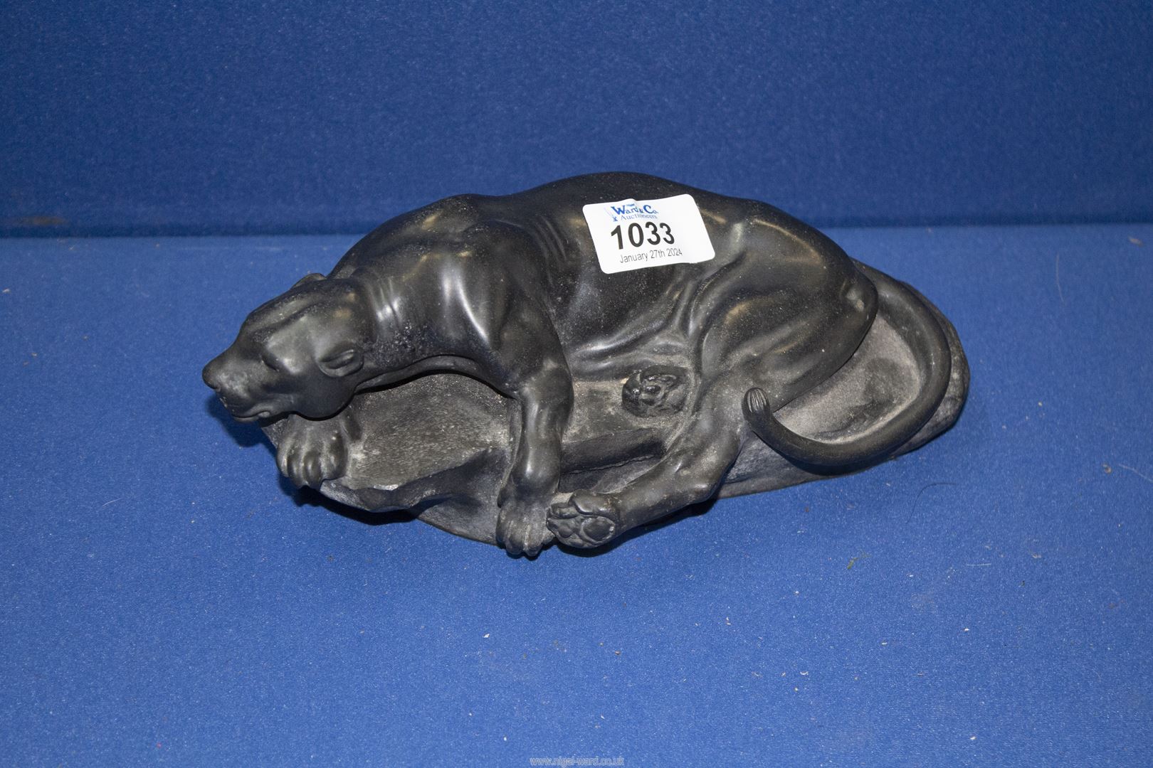 A black marble sculpture of a Puma lying on a rock, signed Masson, 9" long.