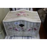 A small serpentine shaped topped miniature Chest finished in cream with pink roses profusely