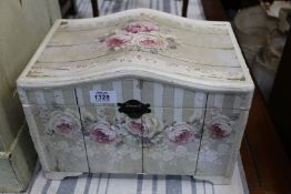 A small serpentine shaped topped miniature Chest finished in cream with pink roses profusely