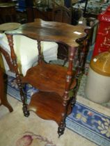 A Rosewood three stage Etagere supported on turned columns terminating with brass castors.