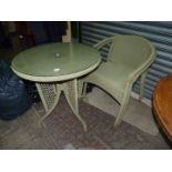 A green cane/woven string Patio conservatory Table having a glass top,