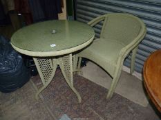 A green cane/woven string Patio conservatory Table having a glass top,