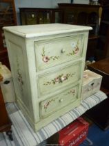 A cream painted Chest of three short Drawers having turned knobs and the drawer fronts decorated