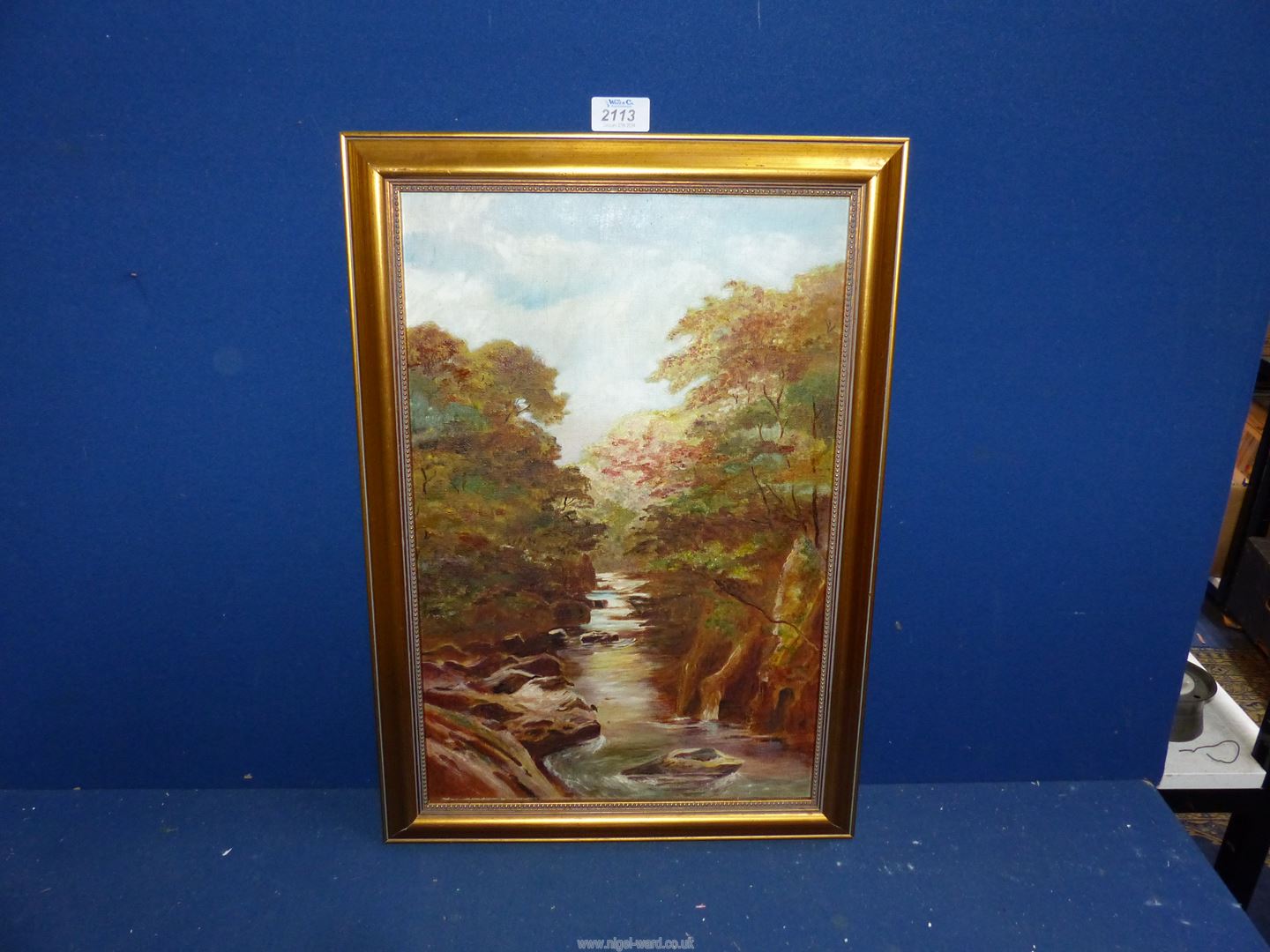 A gilt framed Oil on canvas depicting a river landscape having tree lined banks,