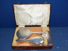 A three piece Art Deco silver dressing/brush set in fitted leather case, Birmingham 1927,
