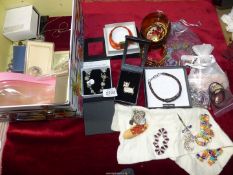 A box of costume jewellery including brooches, colourful beaded bracelet, leather bangles etc.