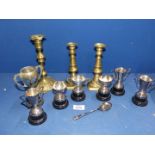 A pair of brass candlesticks with pushers plus one other and a quantity of small metal trophies.