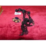 A black bead evening necklace, costume brooch with dark blue polished stones,