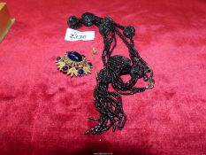 A black bead evening necklace, costume brooch with dark blue polished stones,