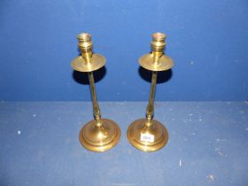 A pair of brass candlesticks with tall narrow stems on wide foot, 12 1/4" tall.