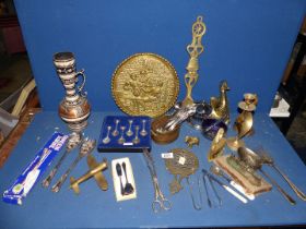 A quantity of mixed metals including cutlery, bell, candlestick, airplane, trivet etc.