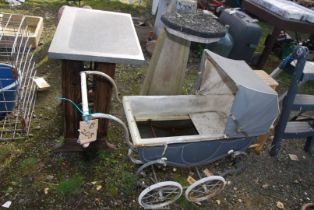 A dolls pram, concrete waste bin stand and a sewing machine table base.