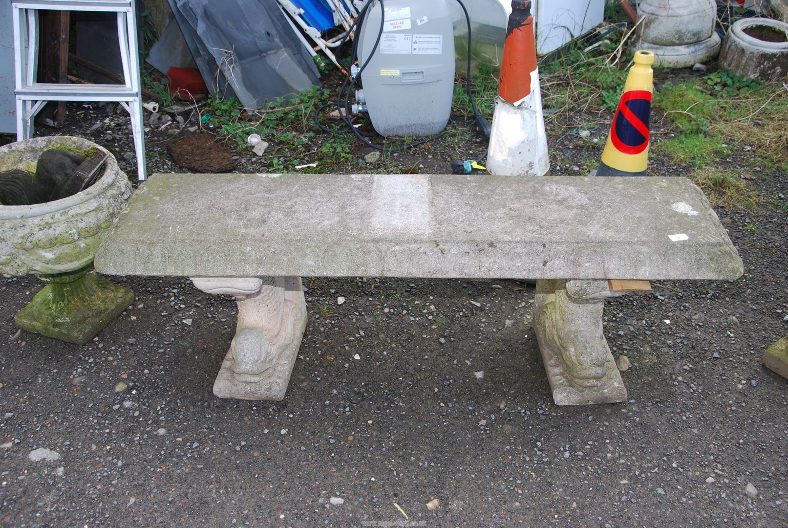 A concrete bench with supports in the form of dolphins, 53'' wide x 15'' deep x 17 1/2'' high.