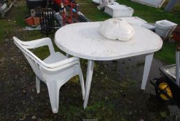 A plastic patio table with two chairs, and a umbrella stand.
