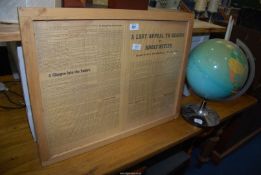 A framed newspaper article and a globe.
