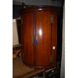 A Mahogany cross banded, cylinder fronted corner Cupboard, with two shelves and key,