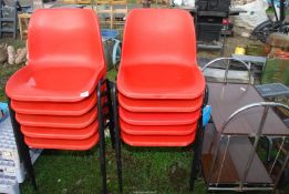Ten red plastic stacking chairs and a tea trolley.
