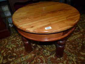 An Eastern hardwood circular Occasional Table standing on turned legs with arched metal braces,