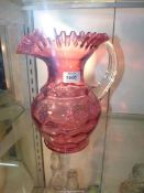 A large Cranberry jug with ruffled rim and a glass clear handle, 9 1/2" tall.