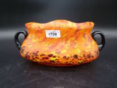 An orange vintage Czech Spatter glass bowl with random colour splashes and having two black handles,