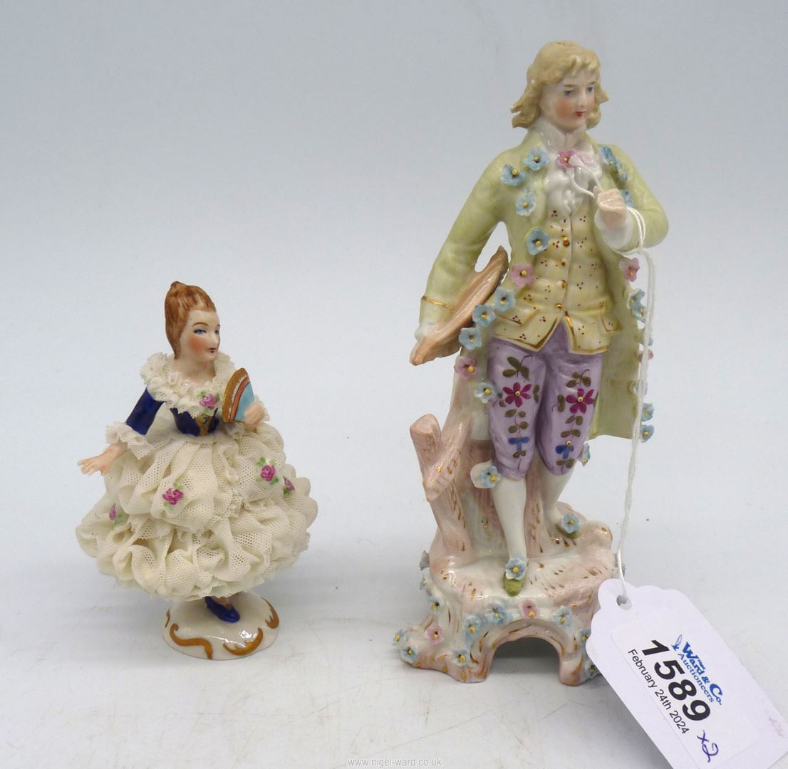 A figure of a man in a period floral encrusted costume and a small Bavarian made figure of a lady
