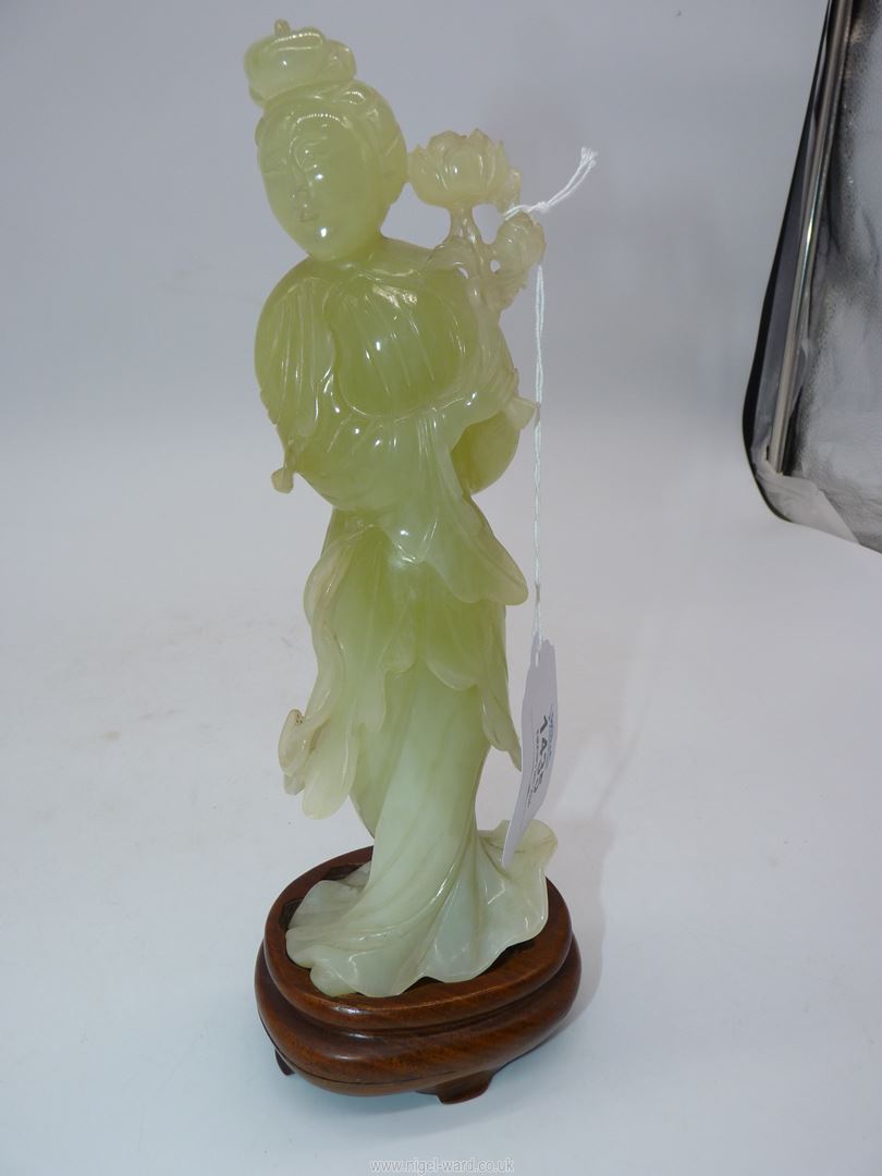 A Jade coloured sculpture of an oriental Geisha figuer in a swirling dress and holding a flower