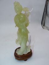 A Jade coloured sculpture of an oriental Geisha figuer in a swirling dress and holding a flower