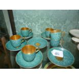 Six Royal Worcester coffee cups and saucers decorated in a blue/green pebble pattern having gilt