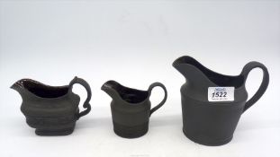 Three black basalt jugs with glazed interior, one having moulded strawberry and vine decoration.