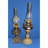 Two oil lamps , one with acanthus leaf base and the other with cast metal base with chimneys.