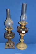Two oil lamps , one with acanthus leaf base and the other with cast metal base with chimneys.