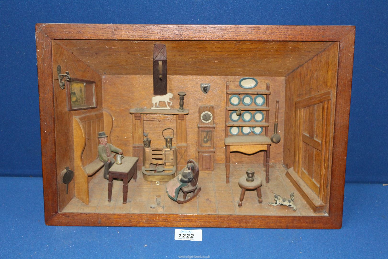 A Black Forest carved Diorama of a room interior with a Grandfather clock, dresser and two figures,