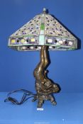 A Tiffany style lamp with ornate stained glass shade with base featuring a gymnast,