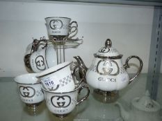 A contemporary tea set in cream and silver lustre, having double 'G' monogram, on stand.
