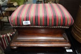 A Mahogany framed Footstool of elegant shape standing on compressed bun feet and upholstered in