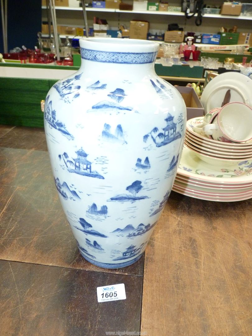 A blue and white oriental vase with overall scenes of pagodas and mountains,