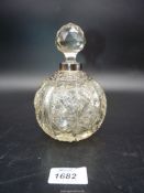 A cut glass dressing table bottle with stopper and silver collar and decoration (hallmarks rubbed).