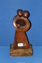 An interesting modernist soft wood carving of parents holding a baby in arms in the style and