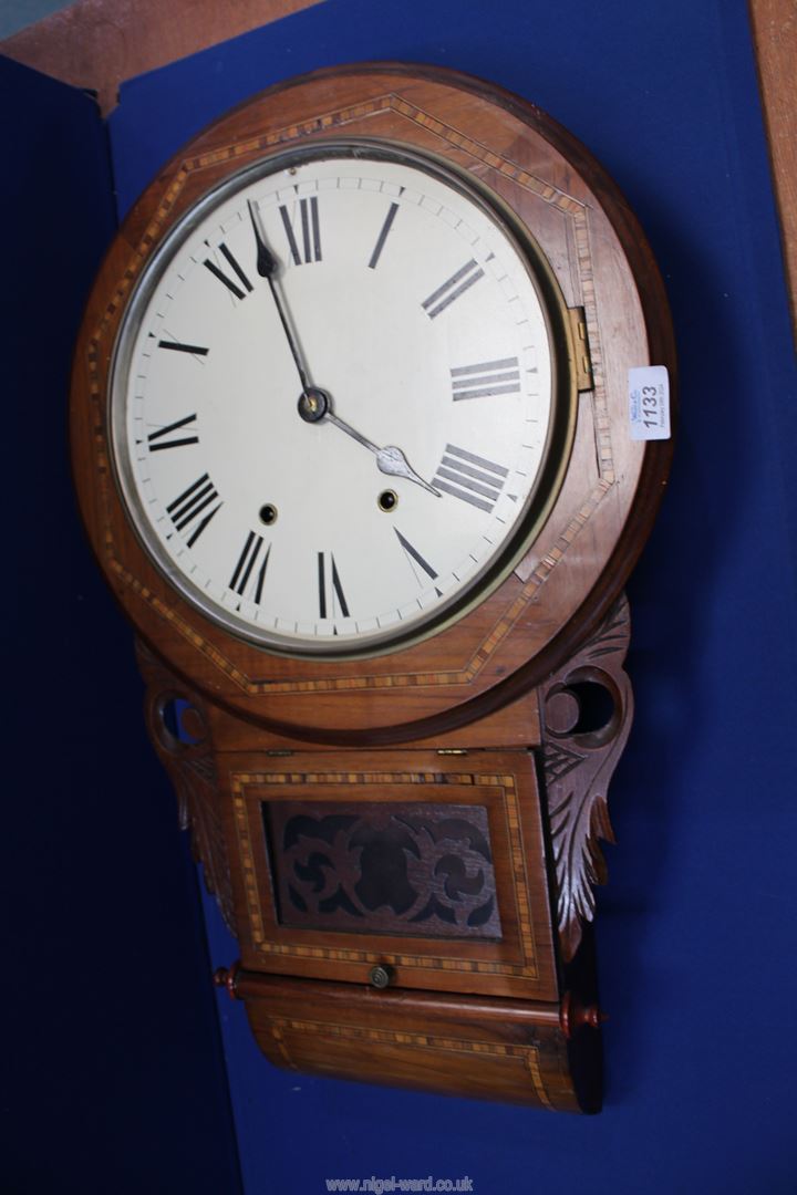 A Wall Clock in a carved and inlaid case with pendulum, key and winder, 27'' high, some damage.