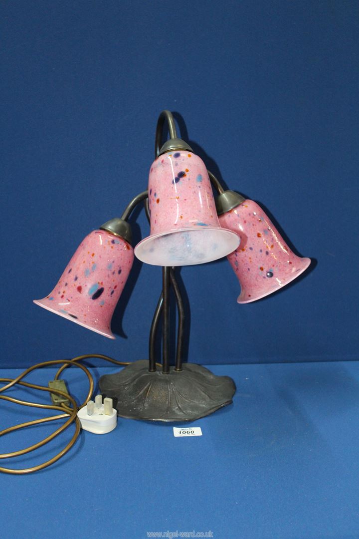 A three branch Lily shaped table lamp with pink and multicoloured mottled glass shades on a cast