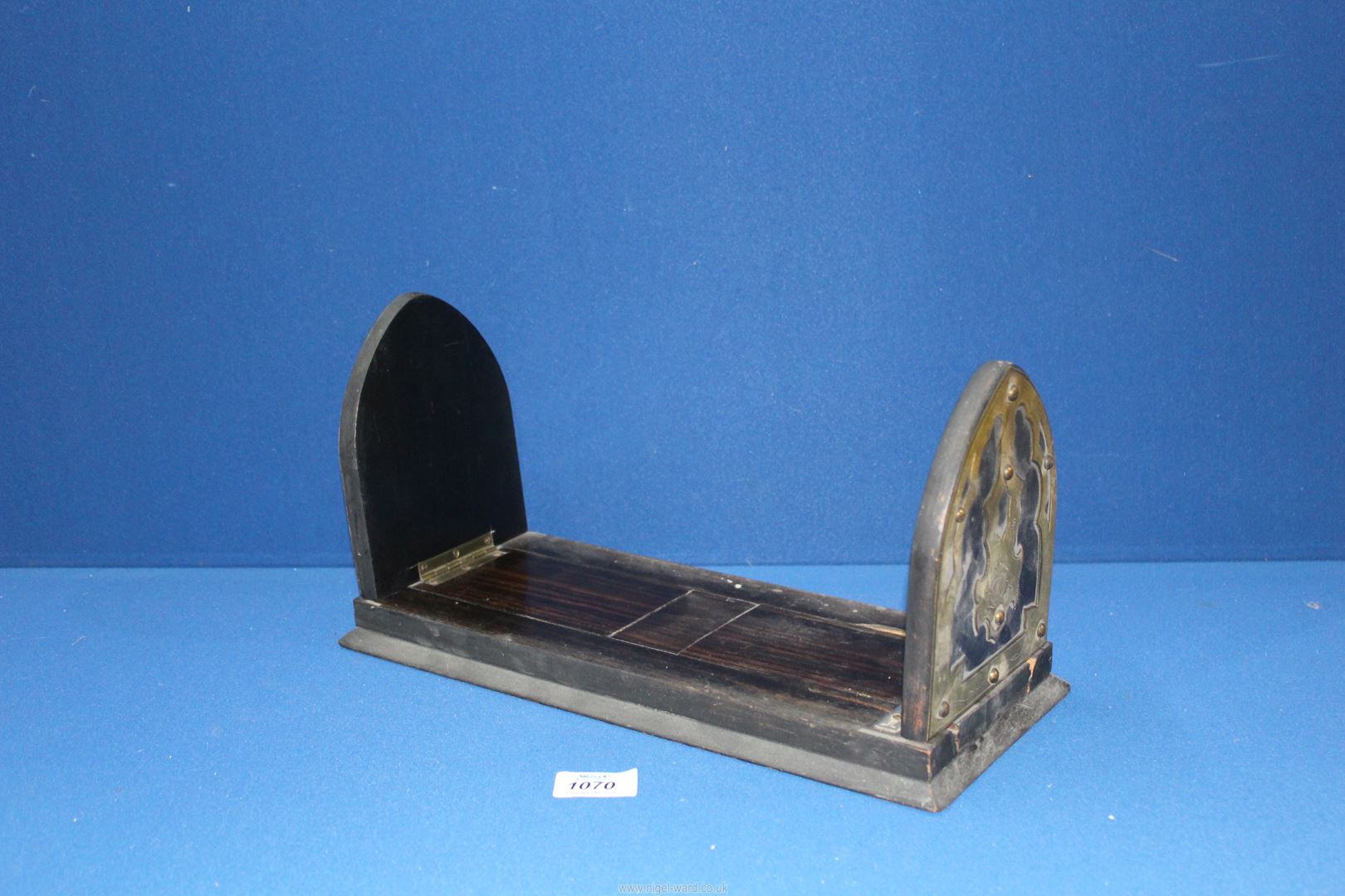 An ebonised book slide with Gothic arch ends and floral brass detail.