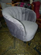 A modern tub shaped Easy Chair upholstered with grey suede style upholstery and standing on