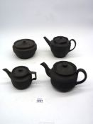 Three black basalt miniature teapots with geometric pattern turning to body of teapots,