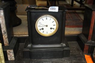 A plain slate chiming Mantle Clock having Roman numerals on a white face and a clear glass back