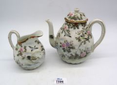 A pretty oriental teapot and milk jug decorated with birds,