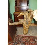 A large piece of driftwood with a carved face of a woman peeping through a gap in the trunk,