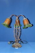 A three branch Lily table lamp having a cast metal floral base and green/orange shades,