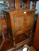 An Old Charm/Priory Oak type Oak Bedside Cabinet having a pair of opposing doors with linen fold