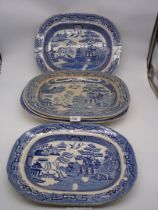 Five blue and white various sized serving Platters in Willow pattern, some with crazing.