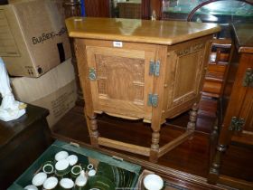 A carved detailed medium Oak canted cornered Cupboard standing on turned legs united by perimeter